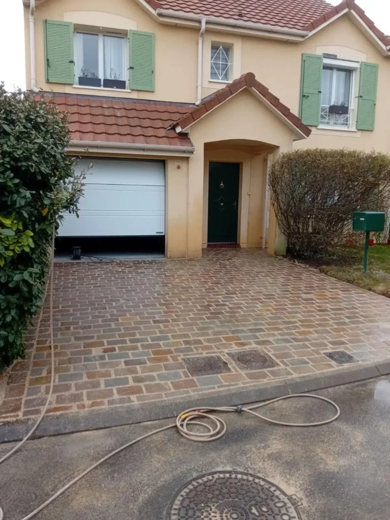 La même entrée terminée en pavés d'Inde, devant une maison aux volets verts